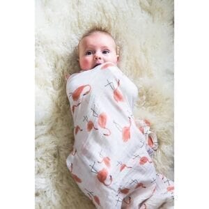 Baby wrapped in white baby swaddle blanket with pink flamingo pattern